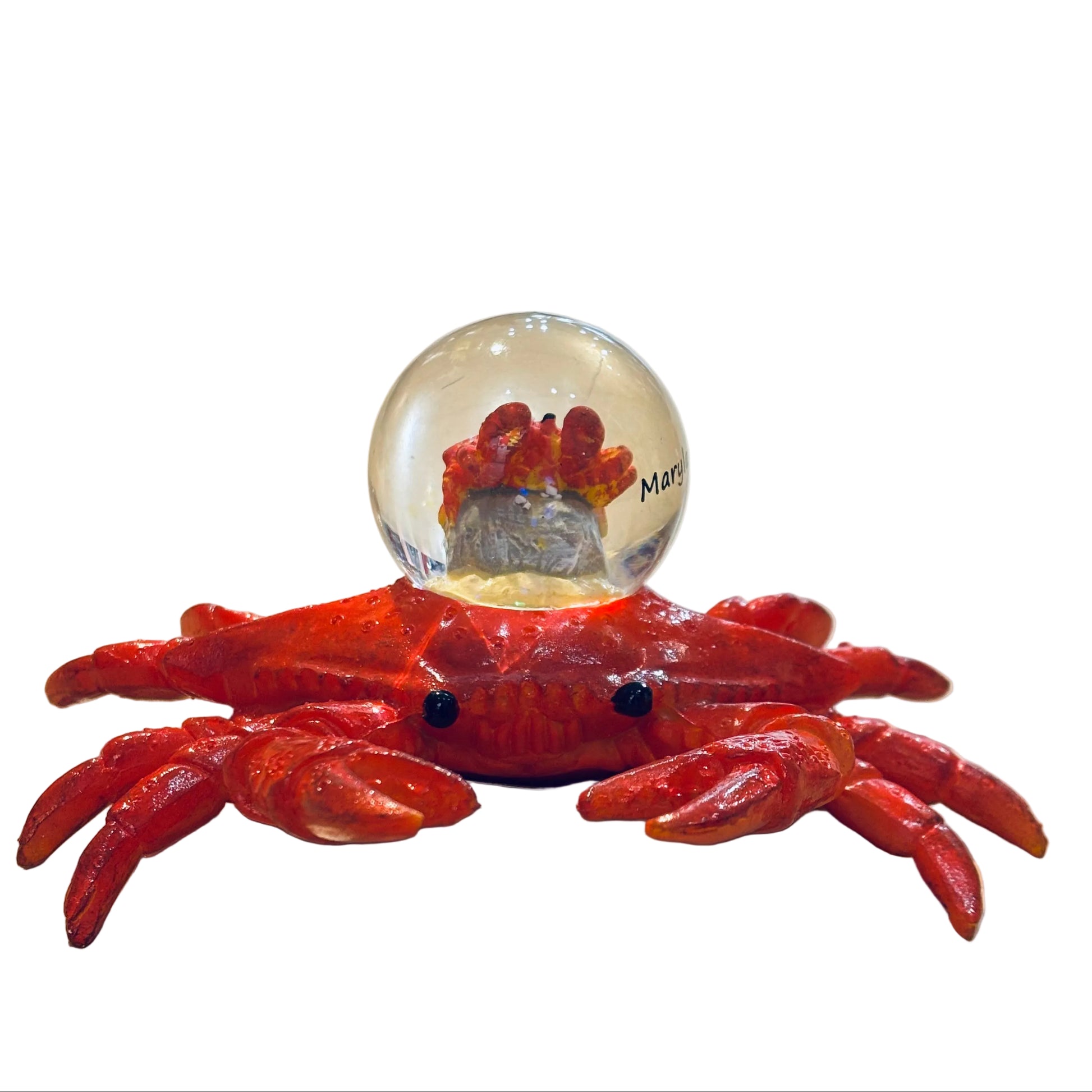 Red crab-shaped object with a clear ball containing a small figurine on a light-colored surface.